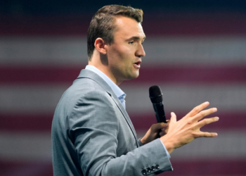 Uma imagem de Charlie Kirk discursando em um evento, representando sua atuação como ativista político.