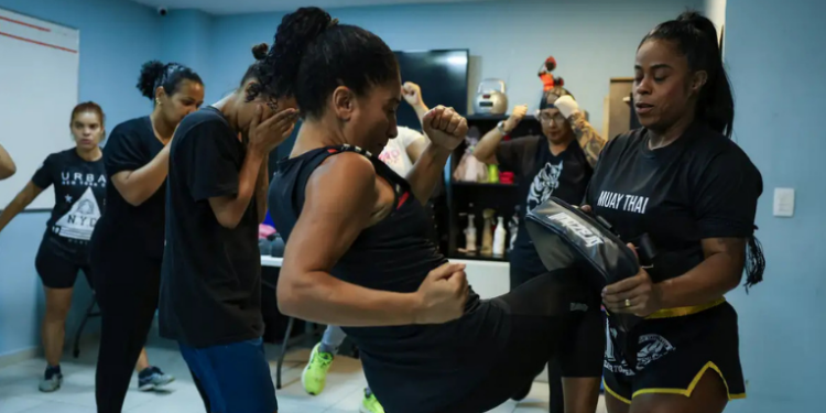A psicanalista Ana Paula Lino superou o trauma da violência doméstica e hoje oferece aulas de Muay Thai para mulheres no projeto Menina-Moça Mulher, no centro do Rio, promovendo empoderamento e autodefesa.