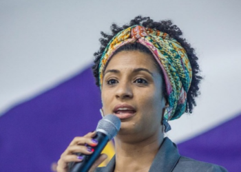  Manifestantes em ato de apoio a Flávio Bolsonaro fizeram comentários ofensivos sobre Marielle Franco perto da PUC-Rio. Familiares criticaram o episódio.