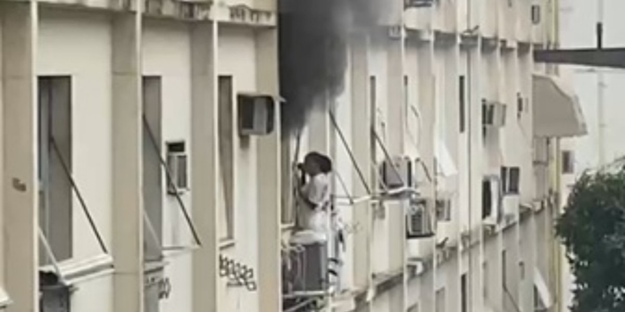 Bombeiros combatem incêndio em apartamento de Copacabana após mulher ser encontrada abrigada no parapeito do prédio.